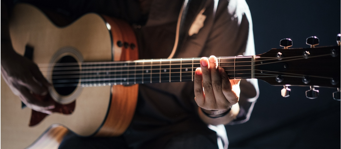 Close up on a person playing the guitar.